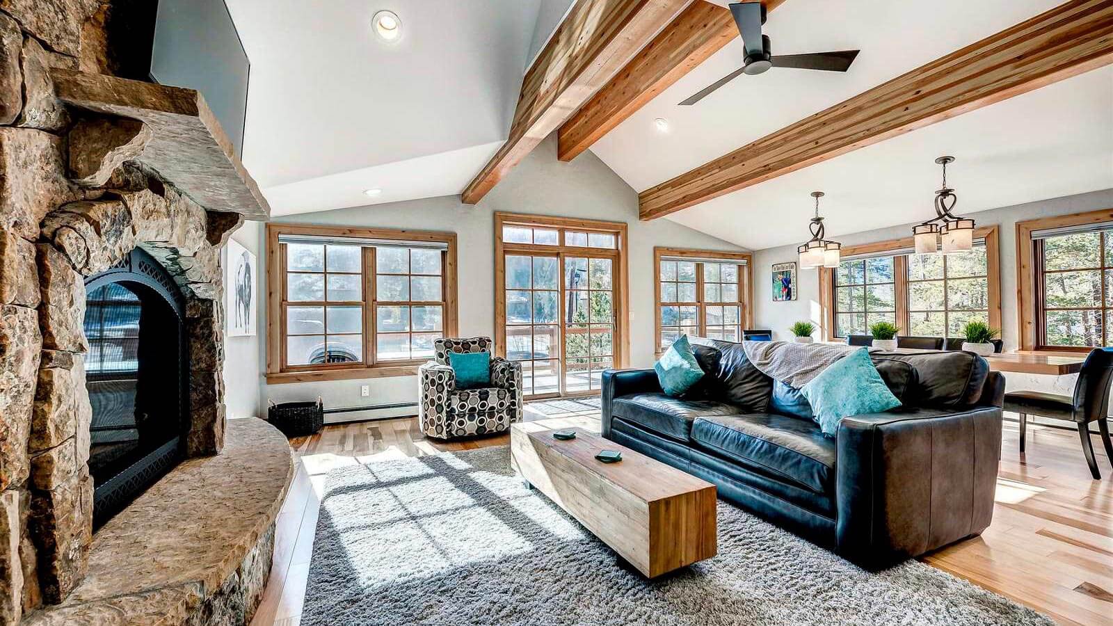 Spacious living area at Frisco Street House featuring vaulted ceilings, exposed wood beams, a stone fireplace, and large
