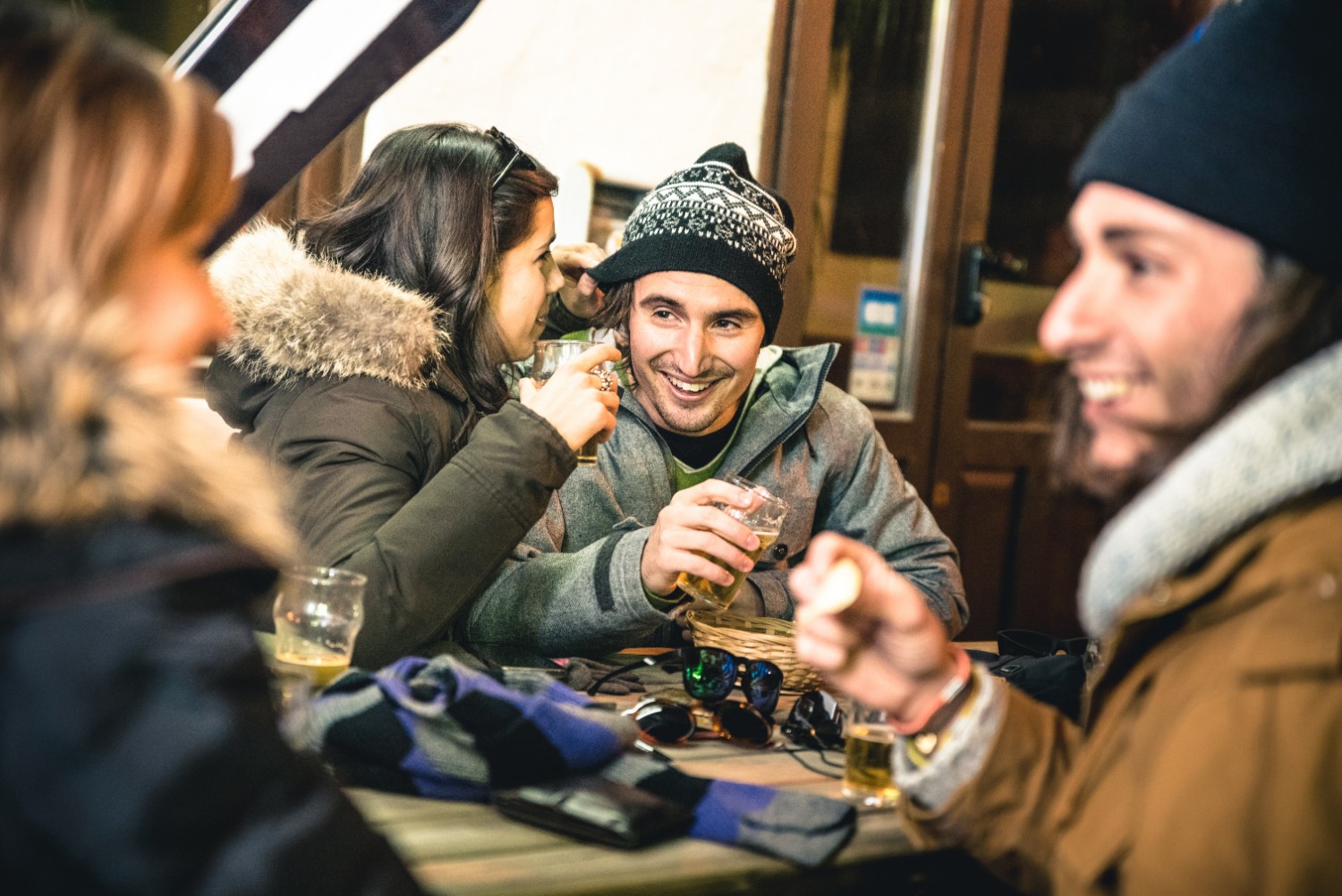 Happy friends drinking beer and eating chips by night at the Ullr Fest in Breckenridge, CO