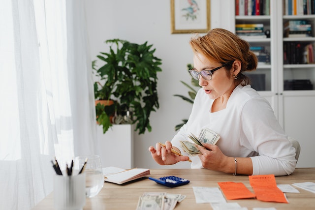 person counting cash and using a calculator at their desk