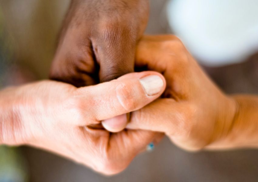 three people joining hands to symbolize unity